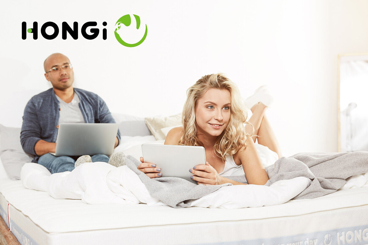 Moderne Werbefotografie für HONGi – junge Menschen mit Laptop und Tablet auf Bett, umgesetzt von Atelier Schulte, professioneller Werbefotograf aus Wien.
