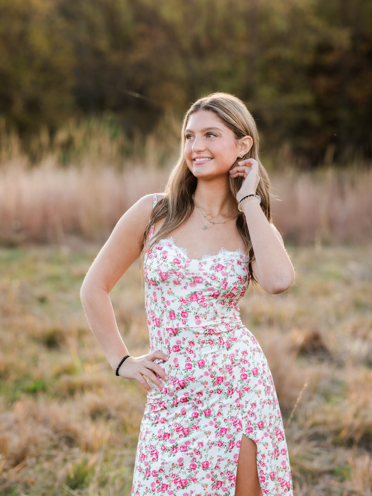 senior girl in floral dress posing for senior photos in field at Westcreek Reservation in Parma, Ohio 