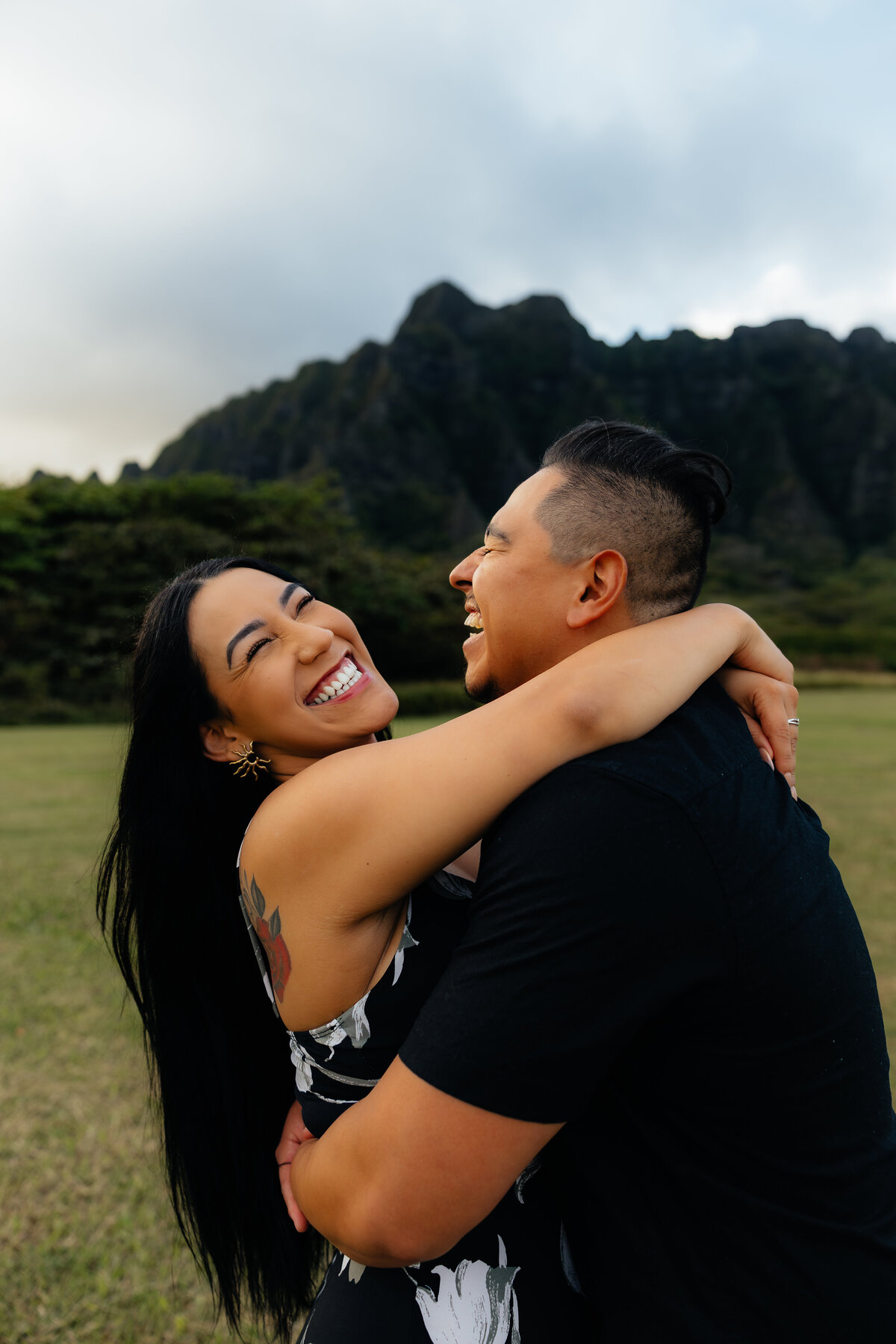 Candid photo of a couple laughing together during their golden hour photoshoot at Kualoa Regional park