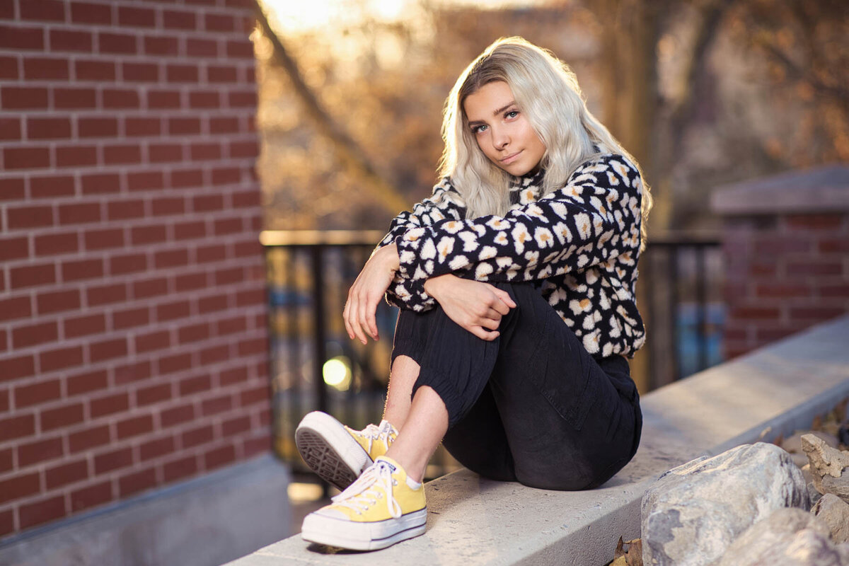 Senior girl posing on brick wall during golden hour during photo shoot at Trolley Square in Utah.