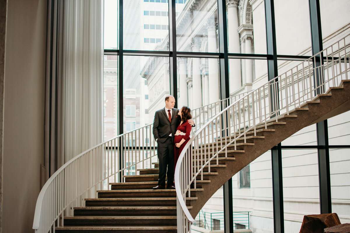 Soon to be mom and dad sharing a moment of love in the middle of a staircase located in the art institute of chicago