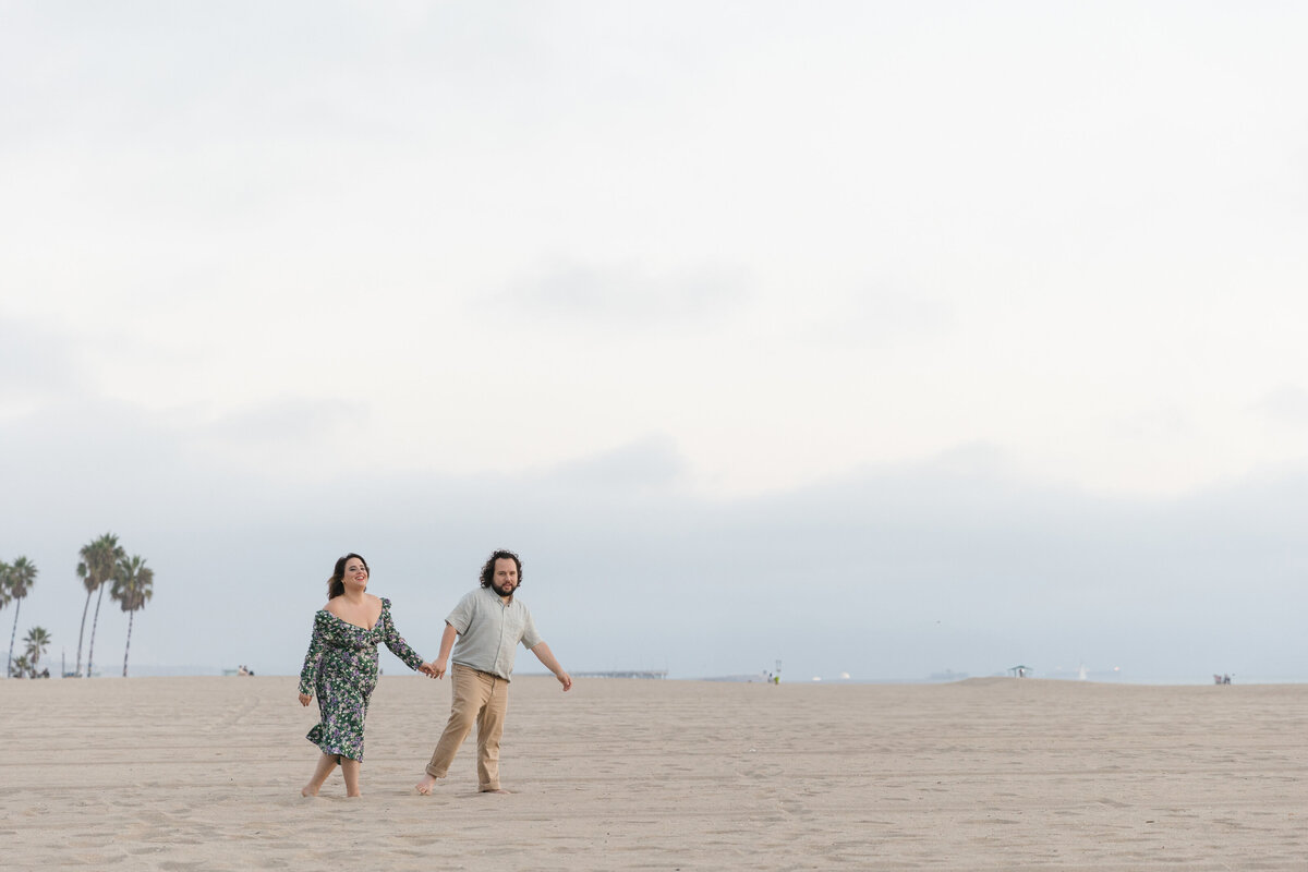 A couple holding hands and walking along the beach