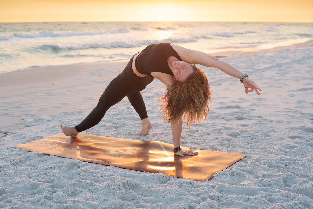 Stephanie in a yoga pose on a sandy beach 