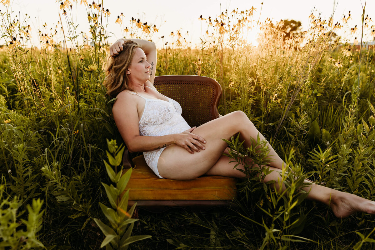 woman in white lingerie sitting in a field of wildflowers on a chair