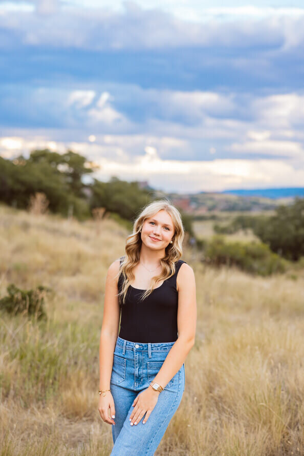 Girl poses for senior photos with red rocks behind her.