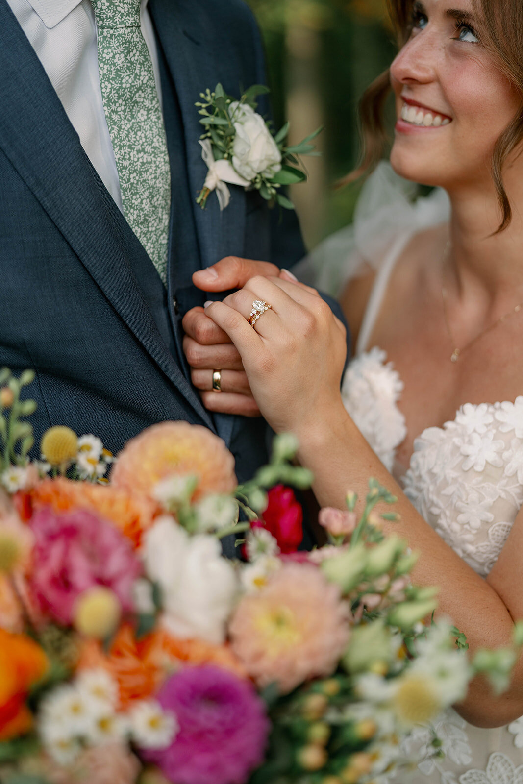Close-up photo of the bride and groom’s hands showing their wedding rings surrounded by their colorful fall wedding flowers during their Cherry Barn wedding in Frankfort,