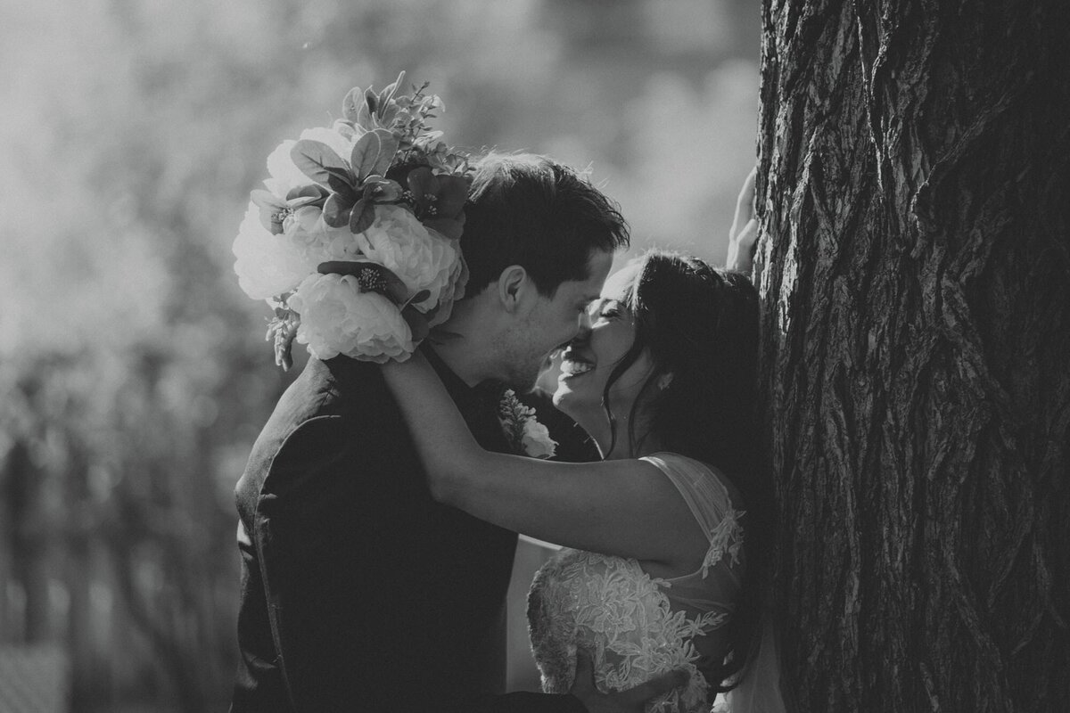 Wedding couple in the moment before a kiss leaning against a tree at The Rouge Restaurant in Calgary