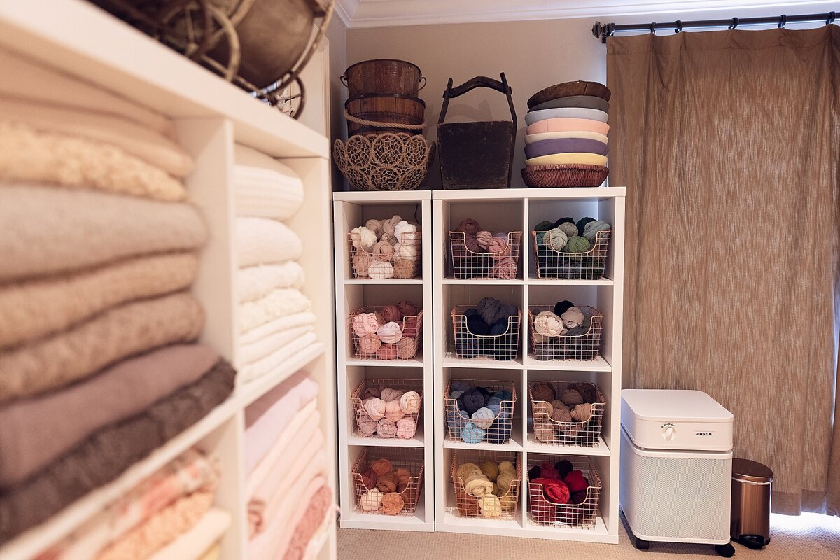 Close-up view of folded blankets and textured fabrics arranged on studio shelves inside a newborn photography studio.