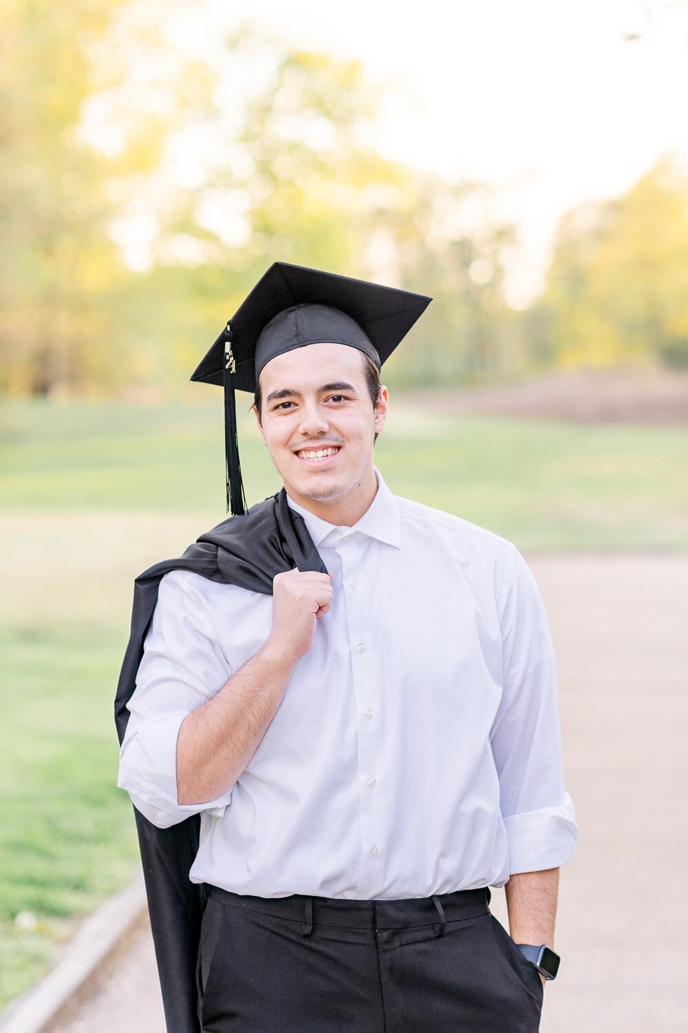teenage boy holding graduation gown during senior mini session in Ashburn, Virginia