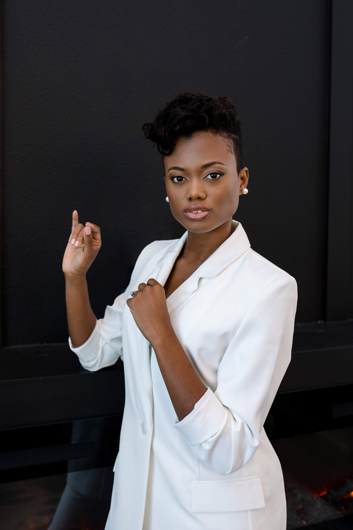 Commercial photographers captures brand of photo head shop with woman in a white blazer posing on a black background for clothing brand photo shoot ideas