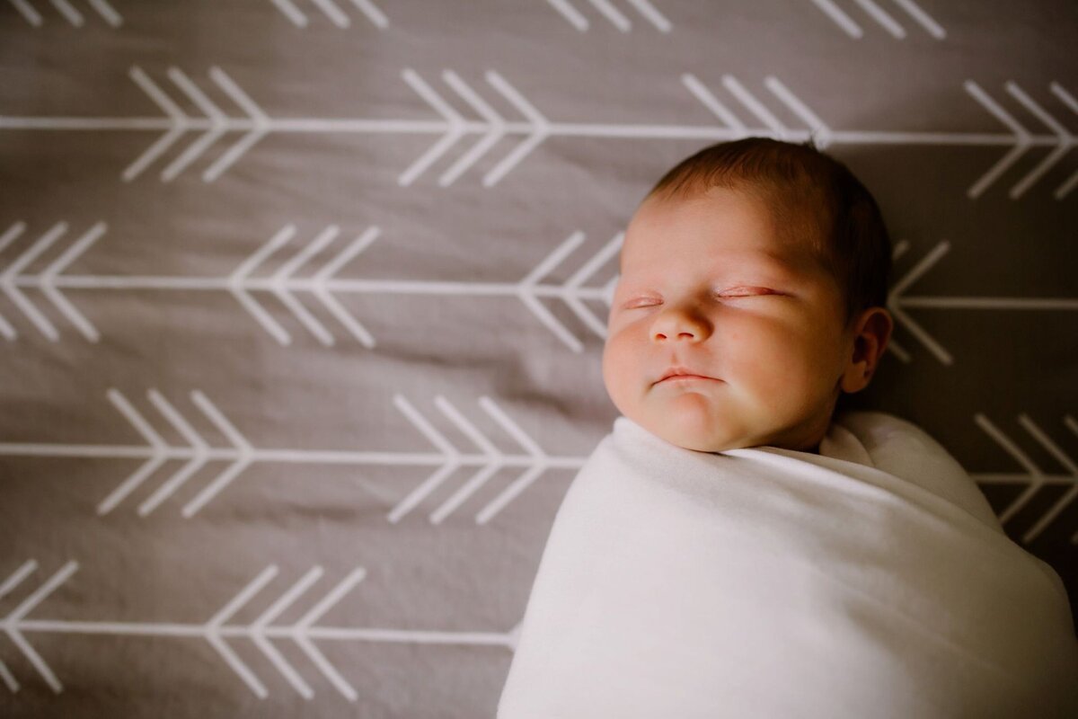 newborn in crib on gray arrow bedding of crib by Francesca Marchese Photography
