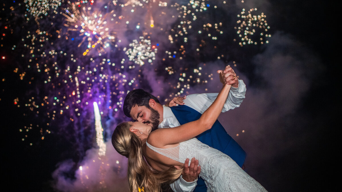 A newly wedding couple kissing under fireworks