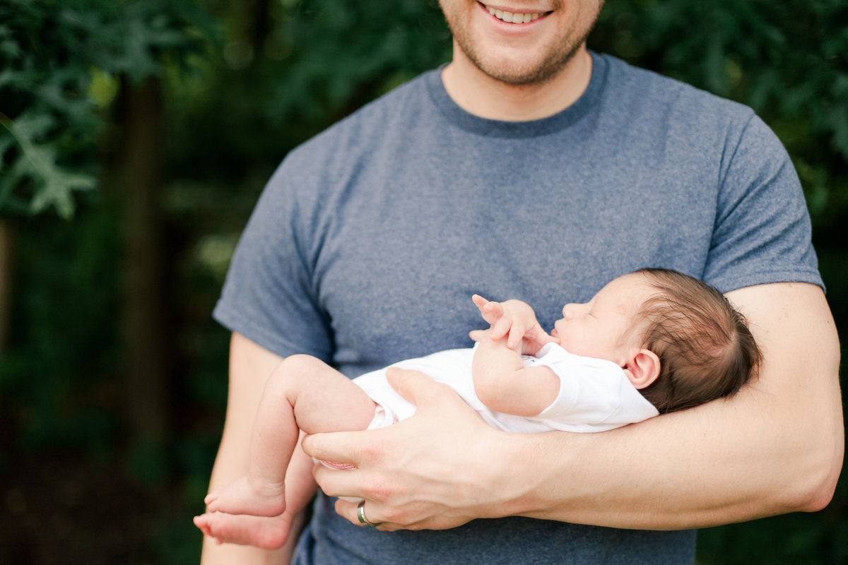 dad with newborn baby son in arms outside newborn photography
