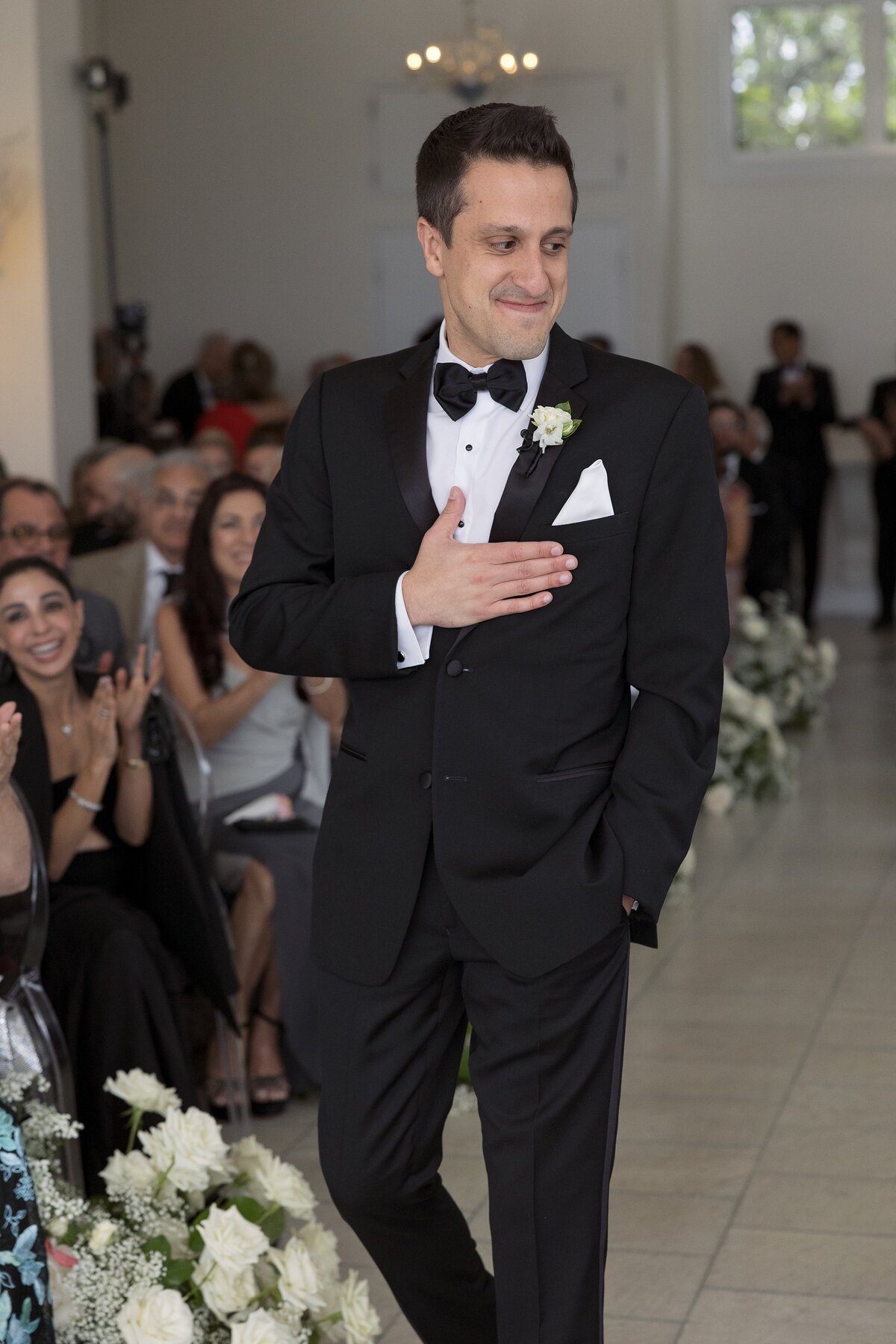 Groom walks down the aisle during indoor wedding ceremony at Belle Mer, Newport.