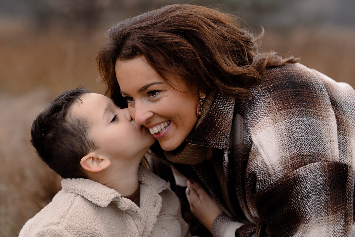 Zoontje fluistert mama iets in haar oor tijdens een motherhoodshoot