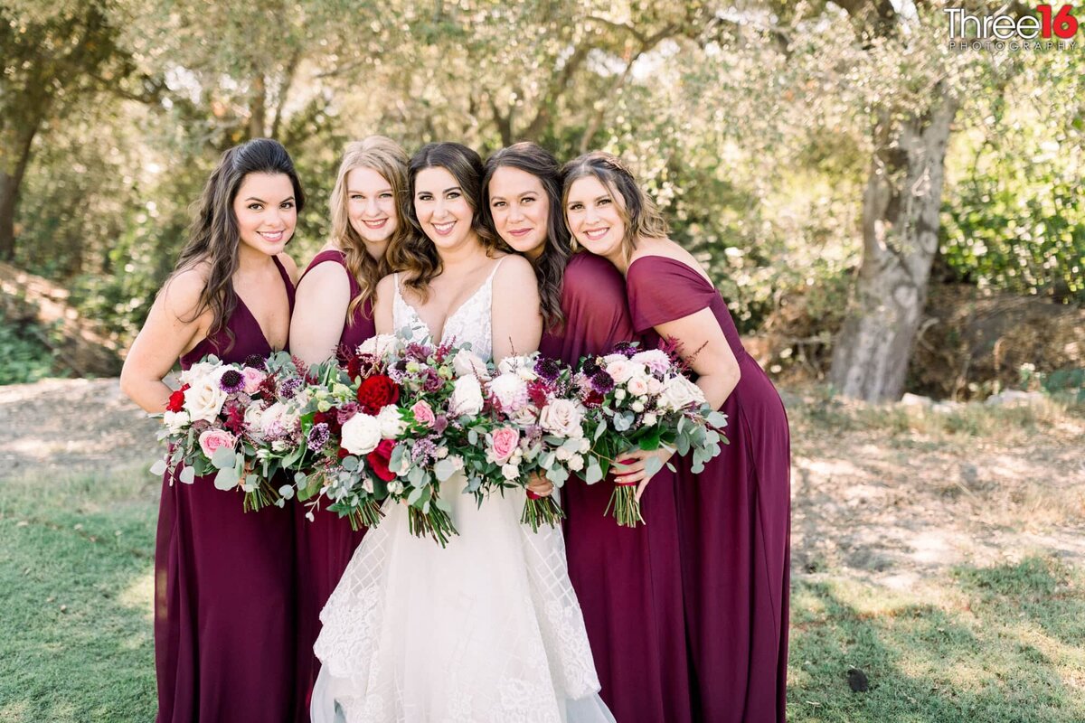Bride and Bridesmaids pose together holding their bouquet of flowers
