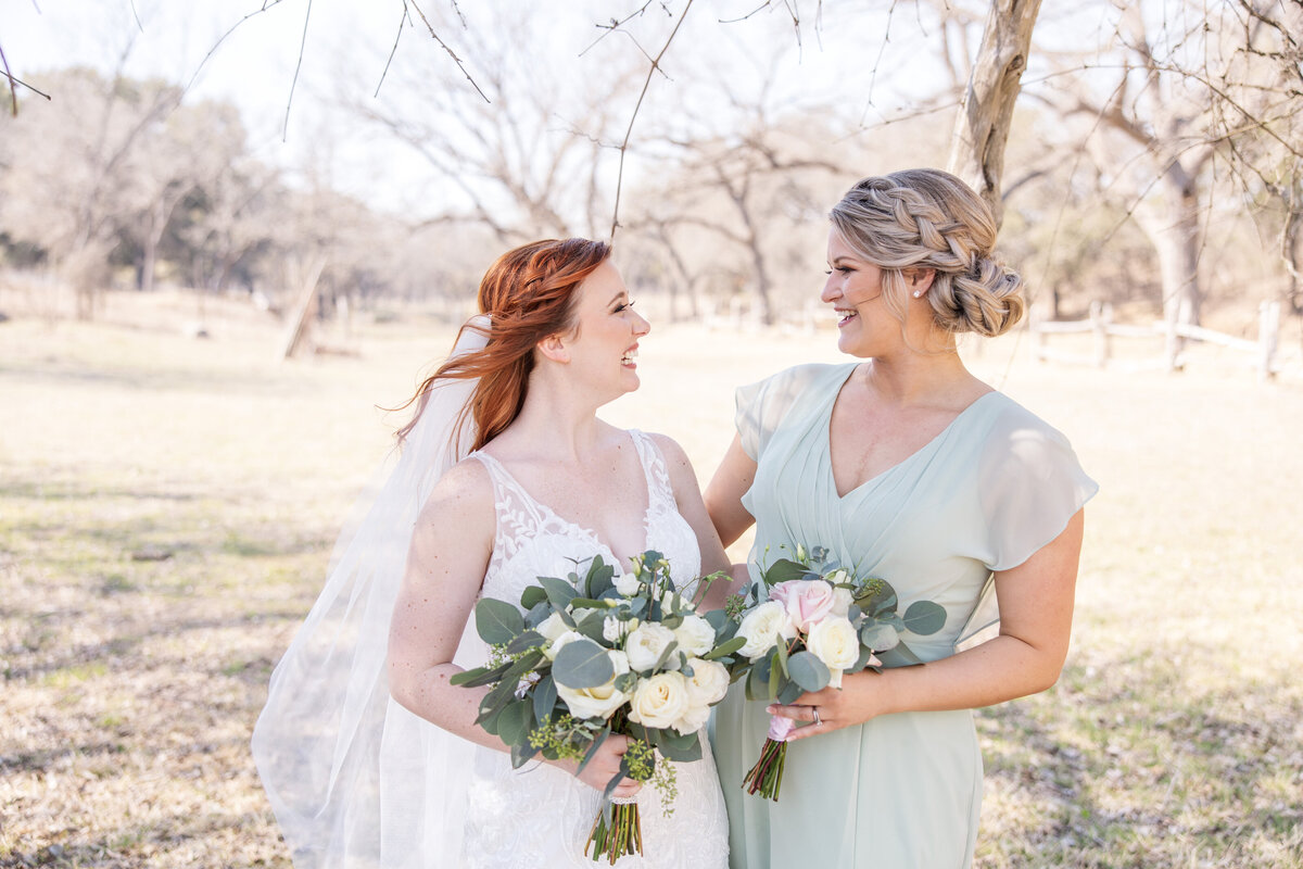red head bride and blonde bridesmaid look to each other and smile