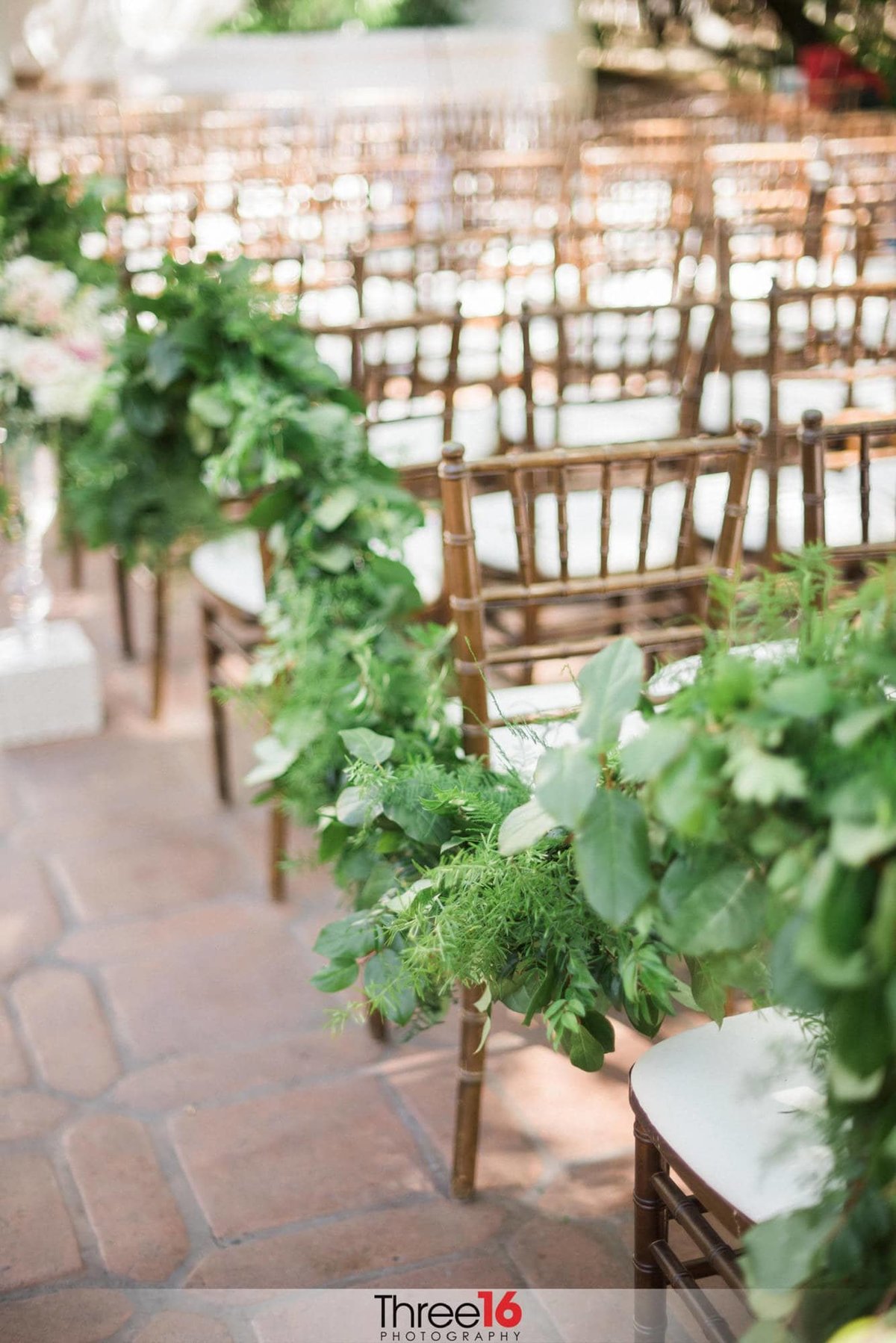Green floral lines the wedding ceremony aisle