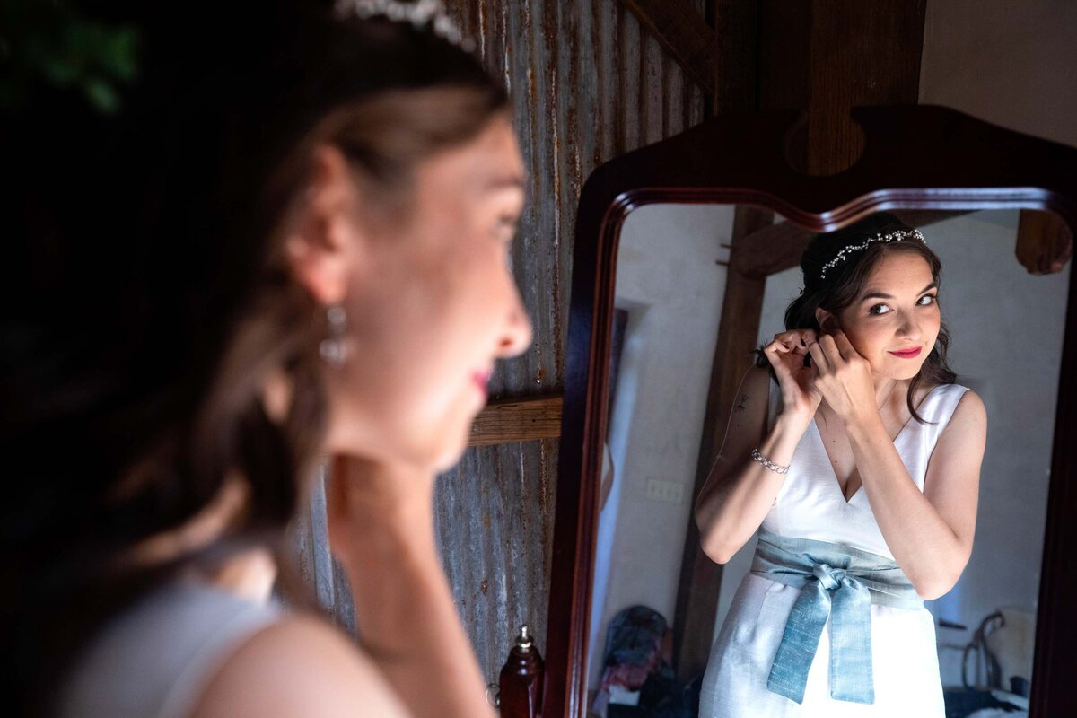 Bride, putting on earings, image of the bride using a mirror to put on earings. Zigbone Farm Retreat, Maryland