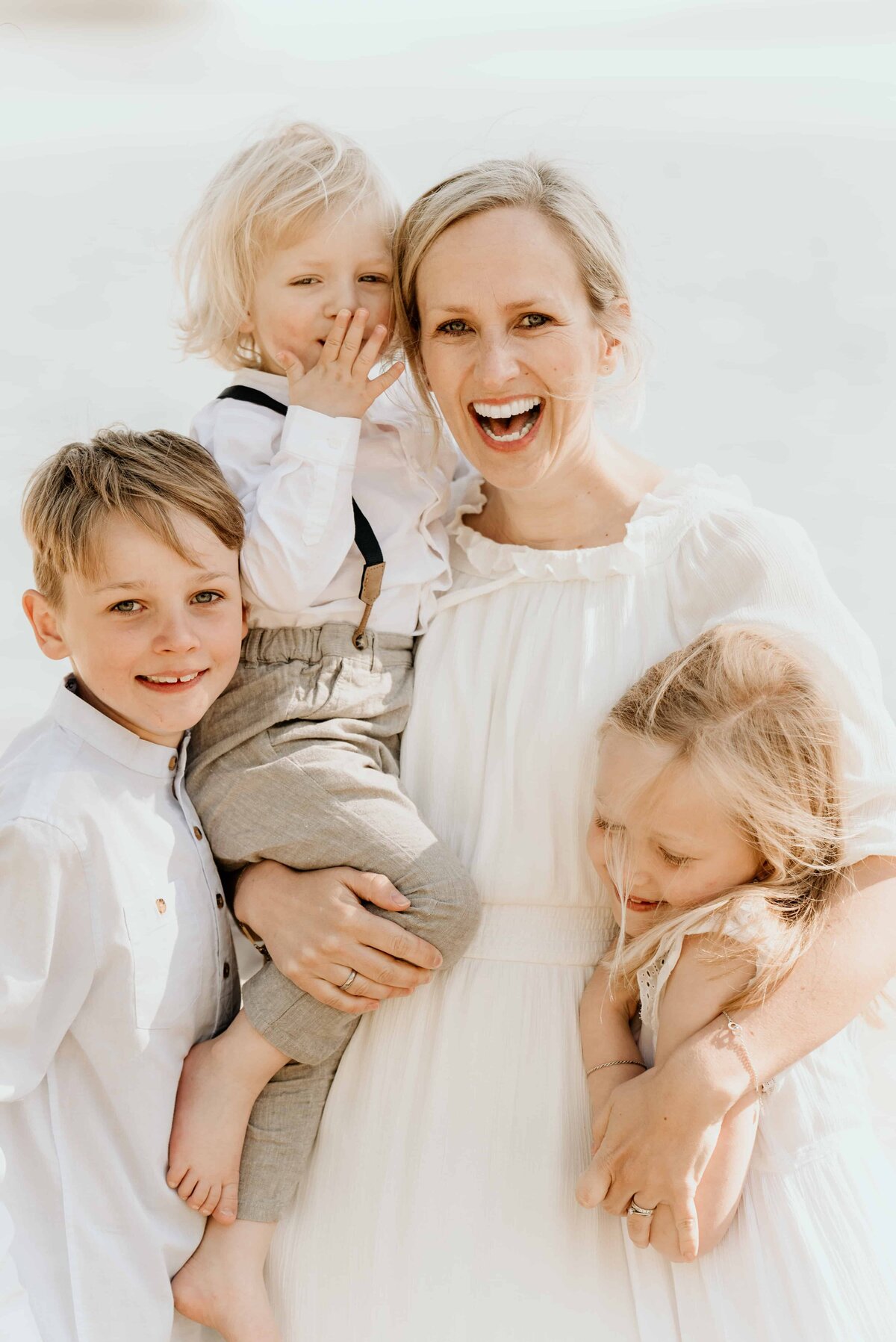 En mor koser med sine tre barn under familiefotografering.