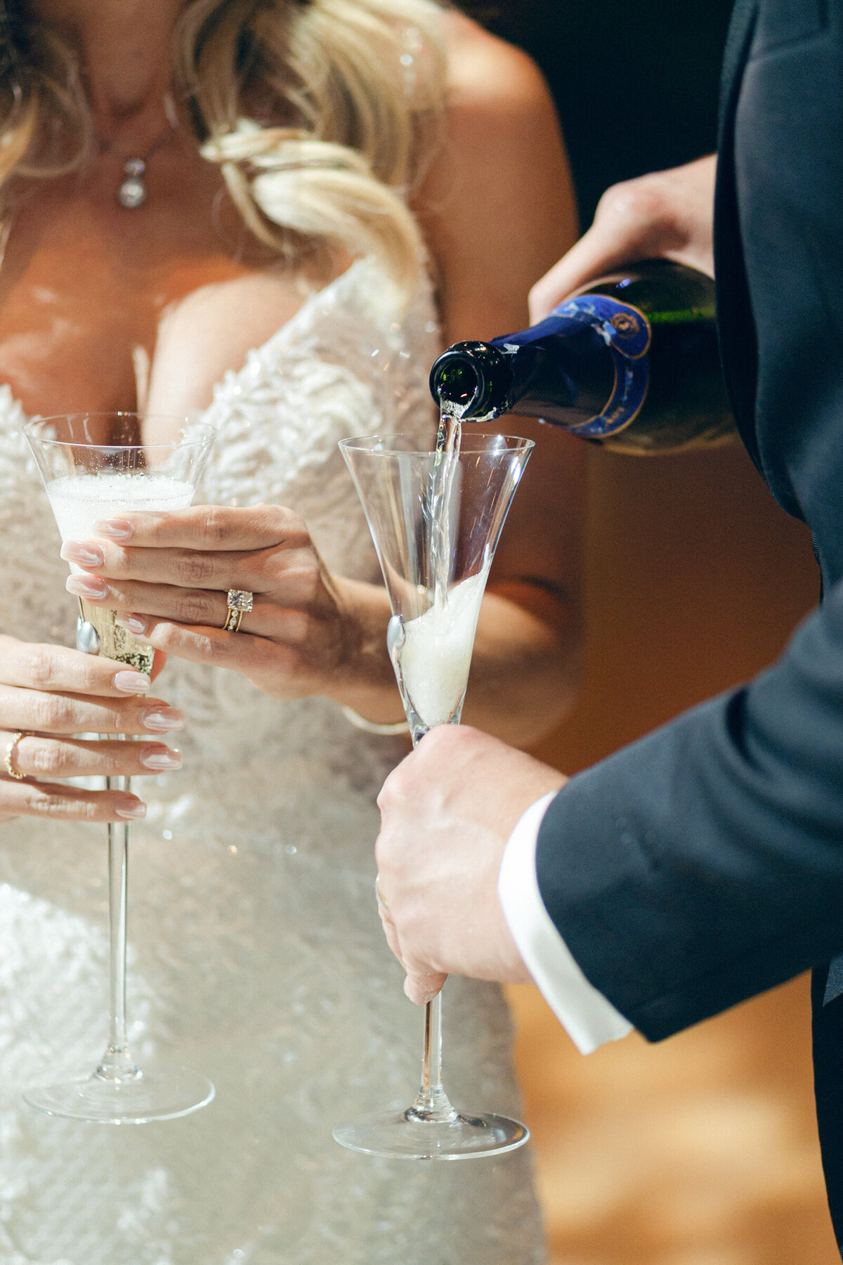 A candid image of the groom pouring a glass of champagne