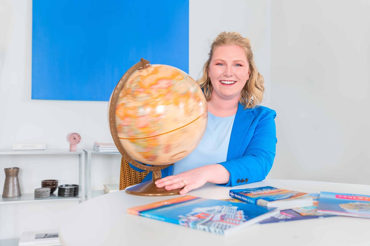 Travel agent client smiling at camera and spinning a globe