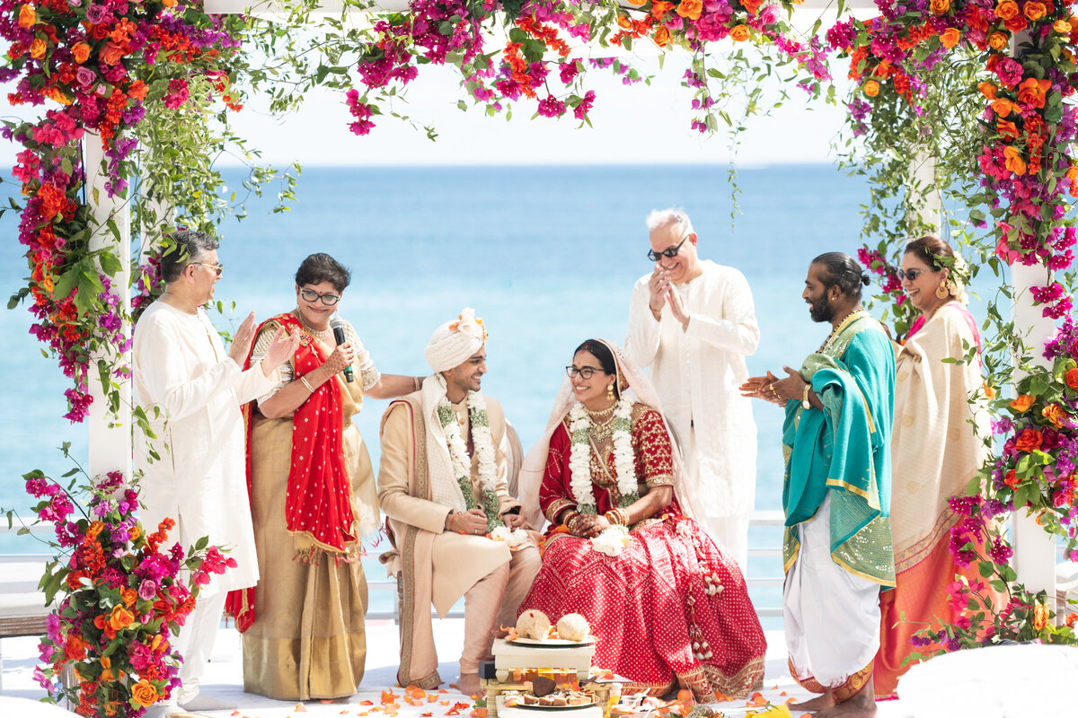 Bride and groom surrounded by family under flower arch