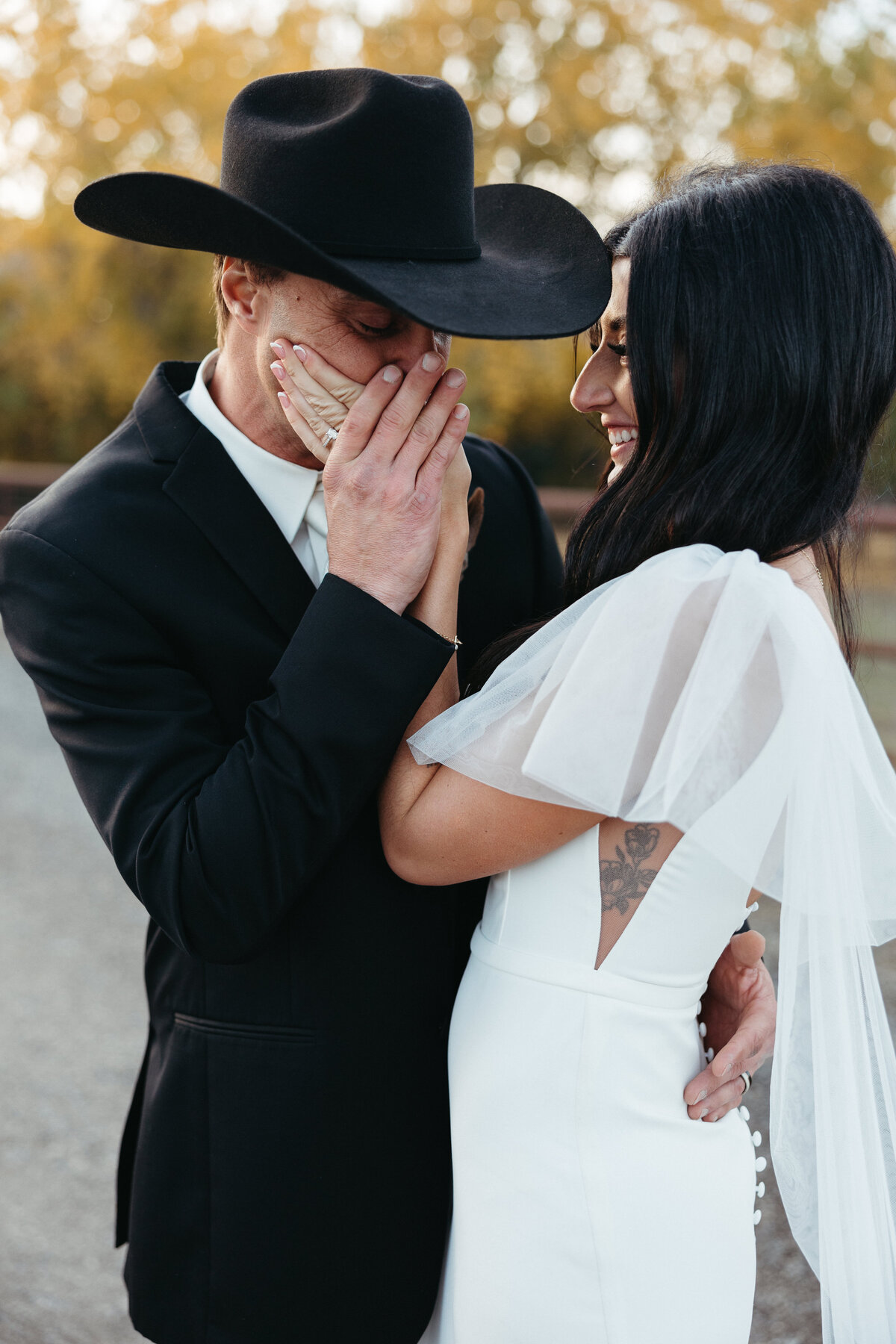 Groom kissing brides hand softly while bride giggles