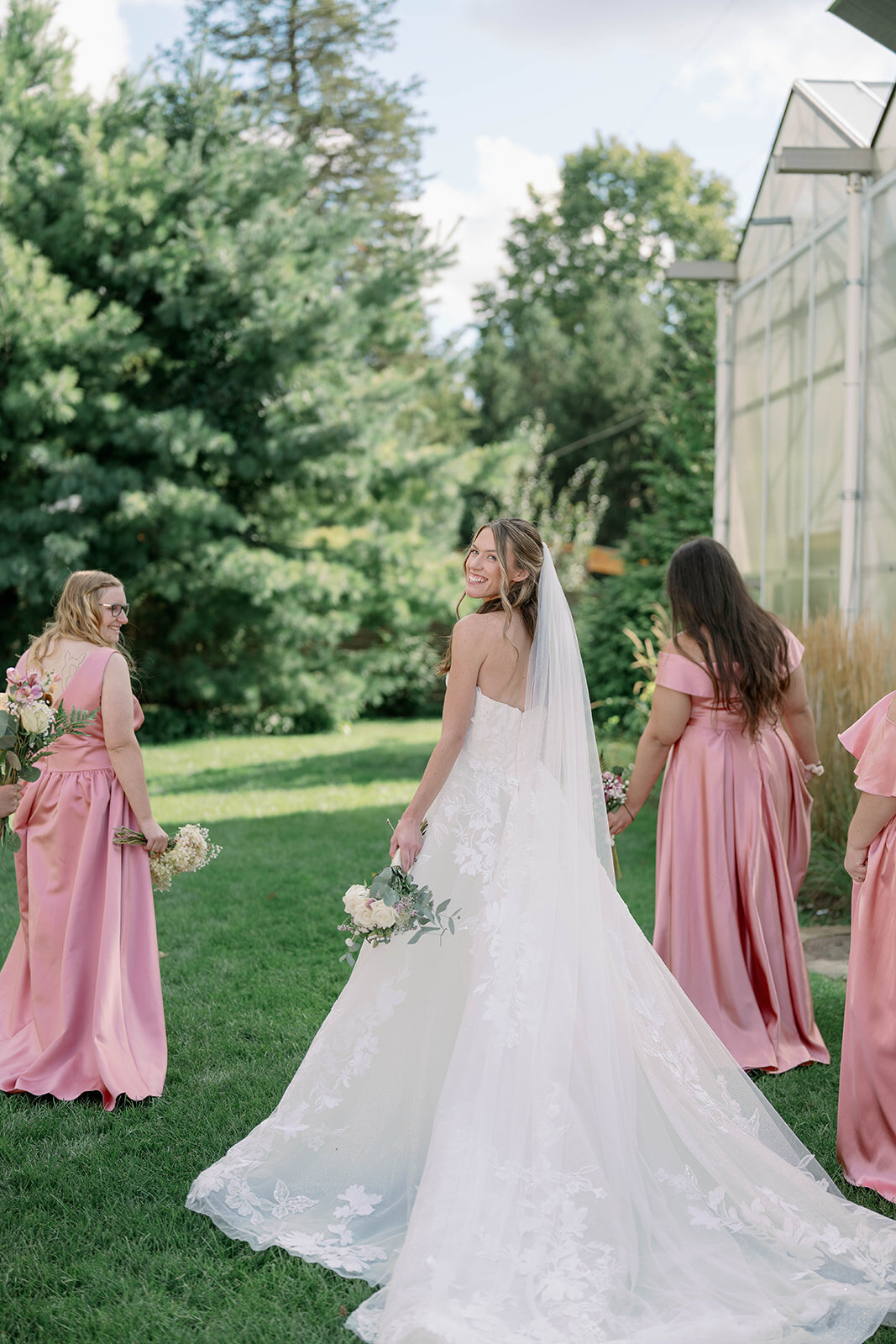 Creative portrait of bridesmaids walking away while the bride smiles over her shoulder at the camera at The Ivy House.
