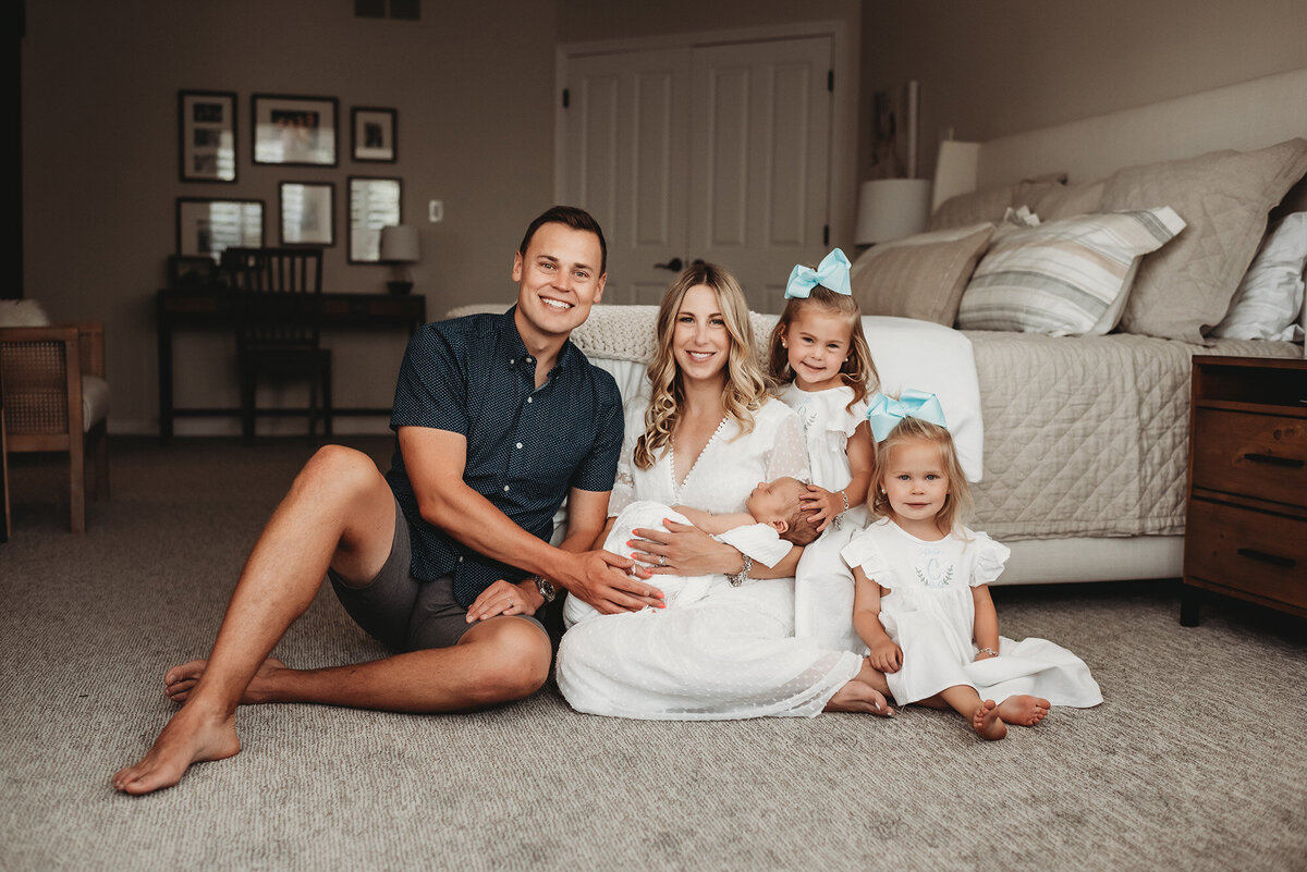 family of five looking at Denver newborn photographer in their home
