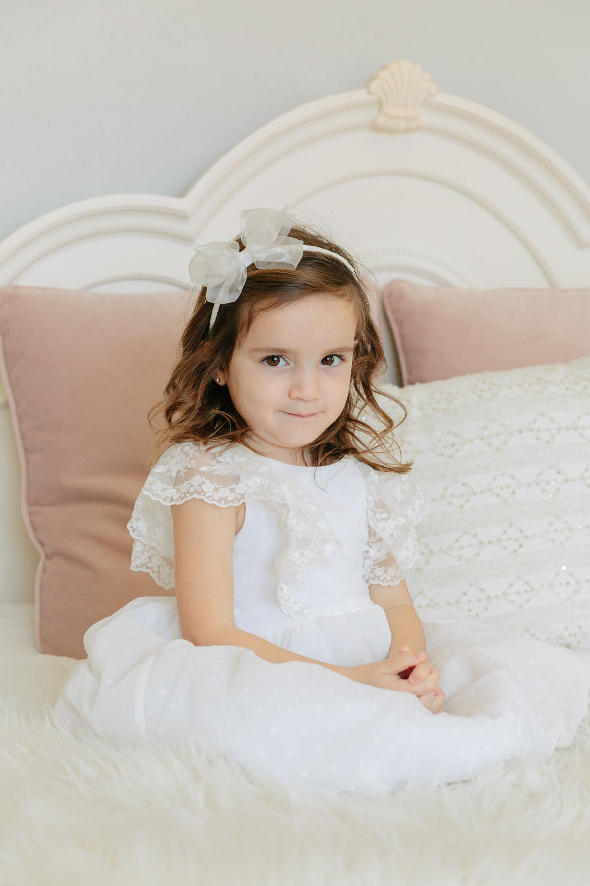 A small girl sitting on a bed smiling