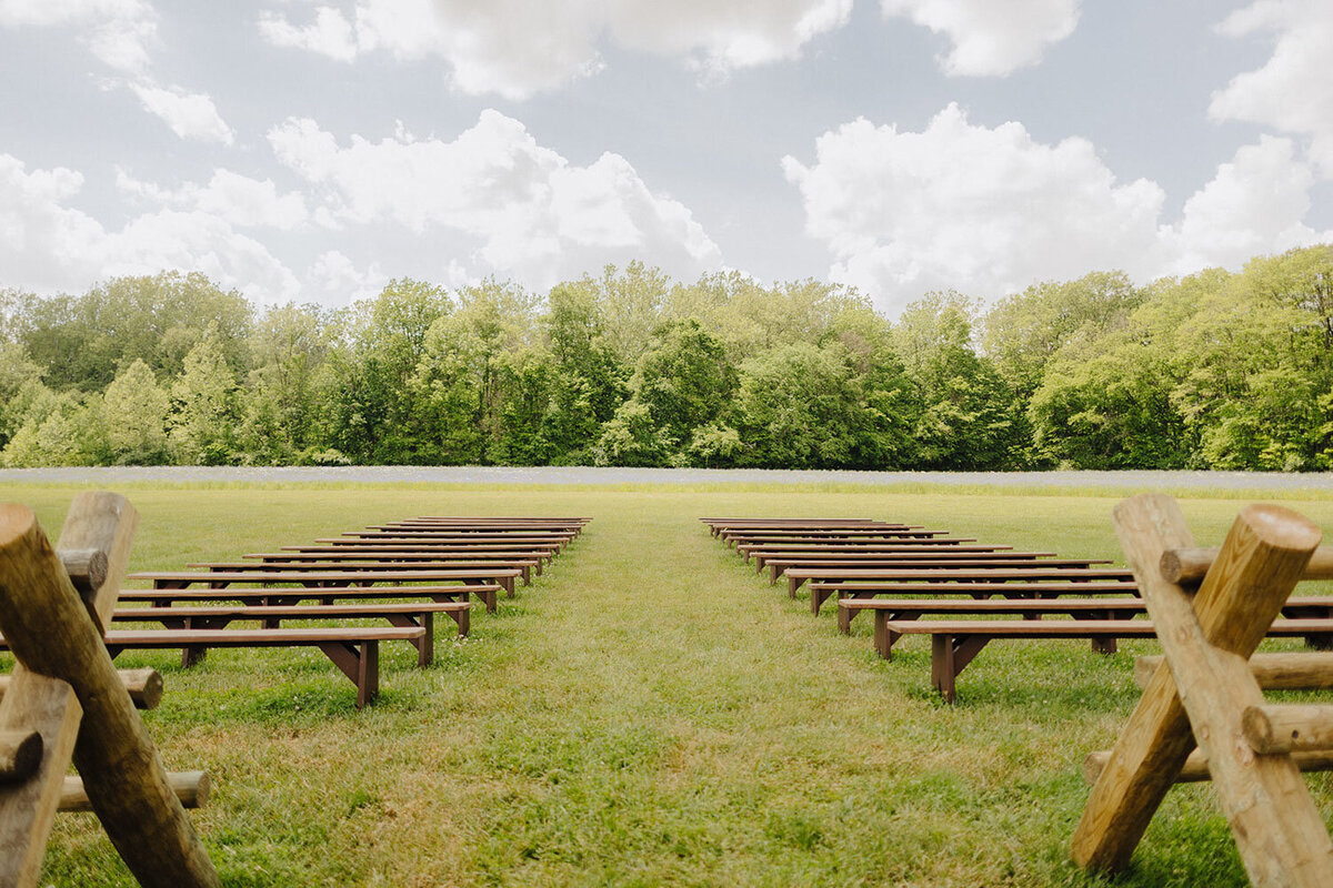 Wooden benches in an outdoor ceremony space facing trees