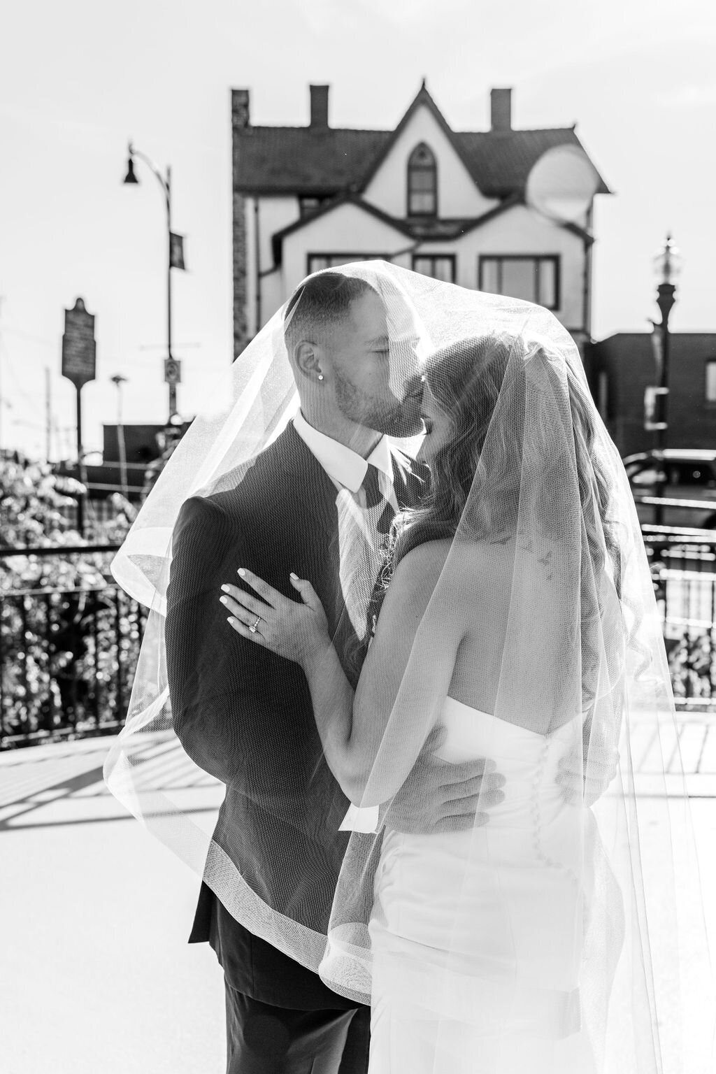 Photo of bride and groom kissing under veil
