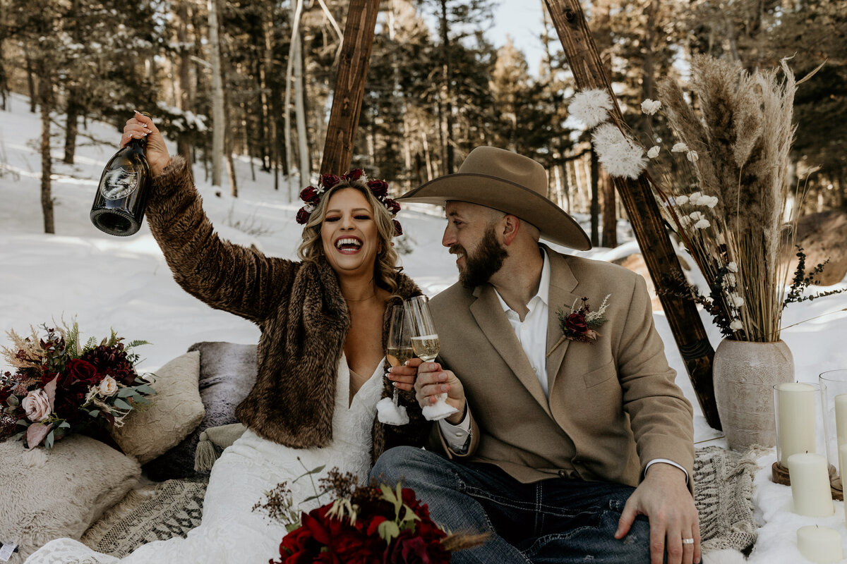 bride and groom drinking champagne in the snow