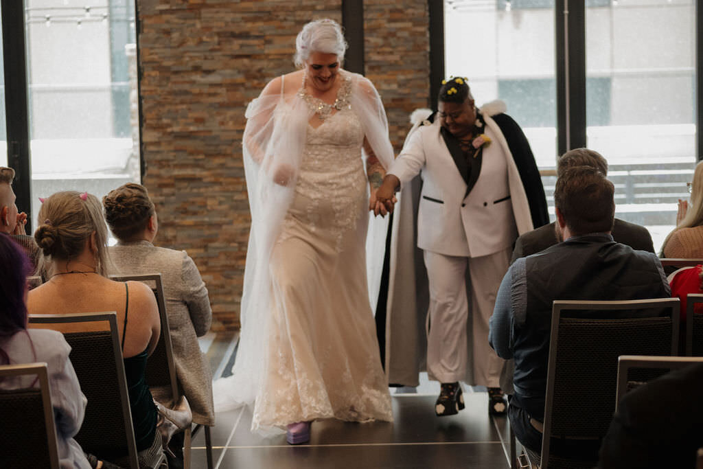 A newlywed couple walking back up the aisle together.