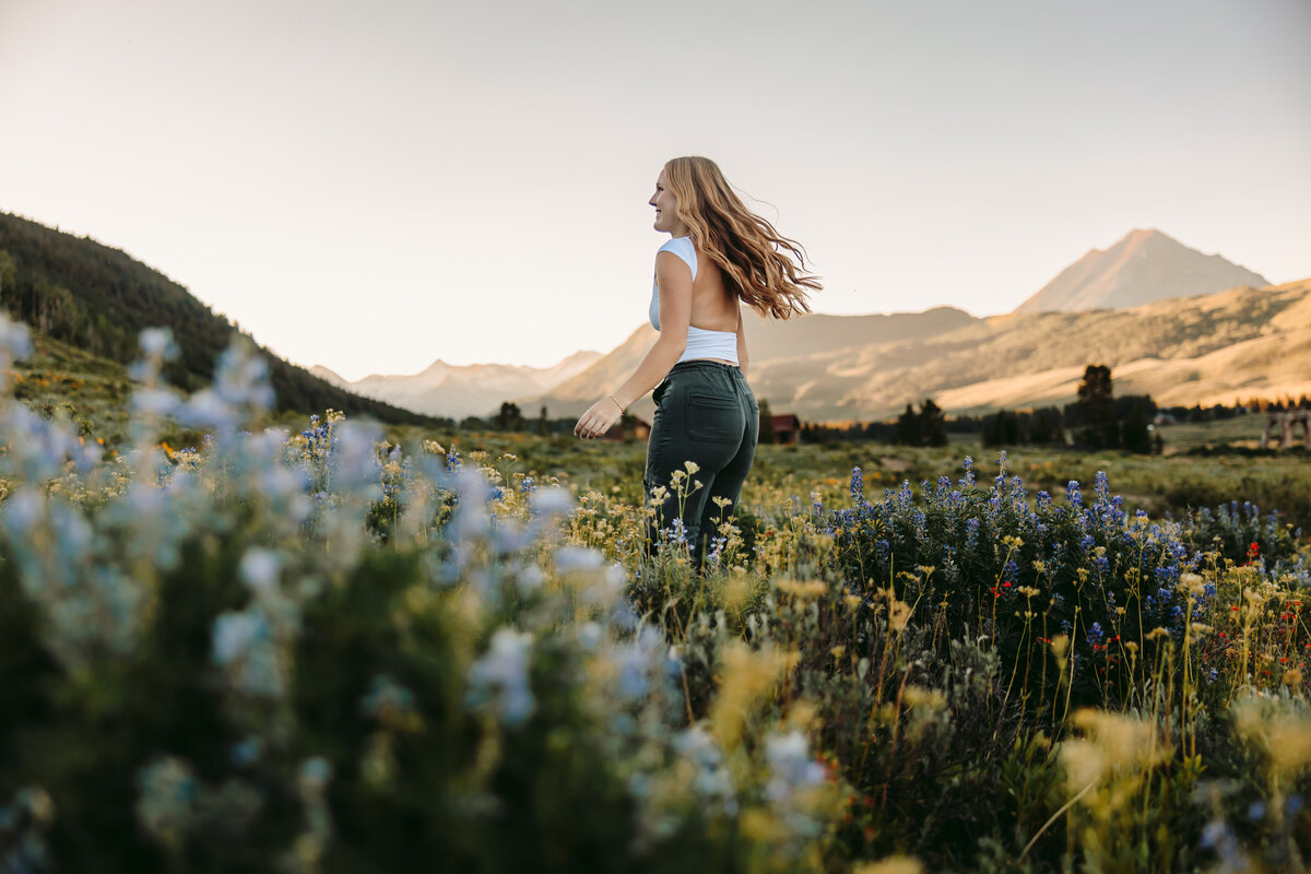 Brenna dances in a field of wildflowers for her Crested Butte senior pictures.