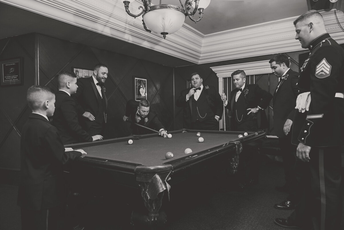 black and white wedding photo of groomsmen playing pool in billiards room at The Carltun
