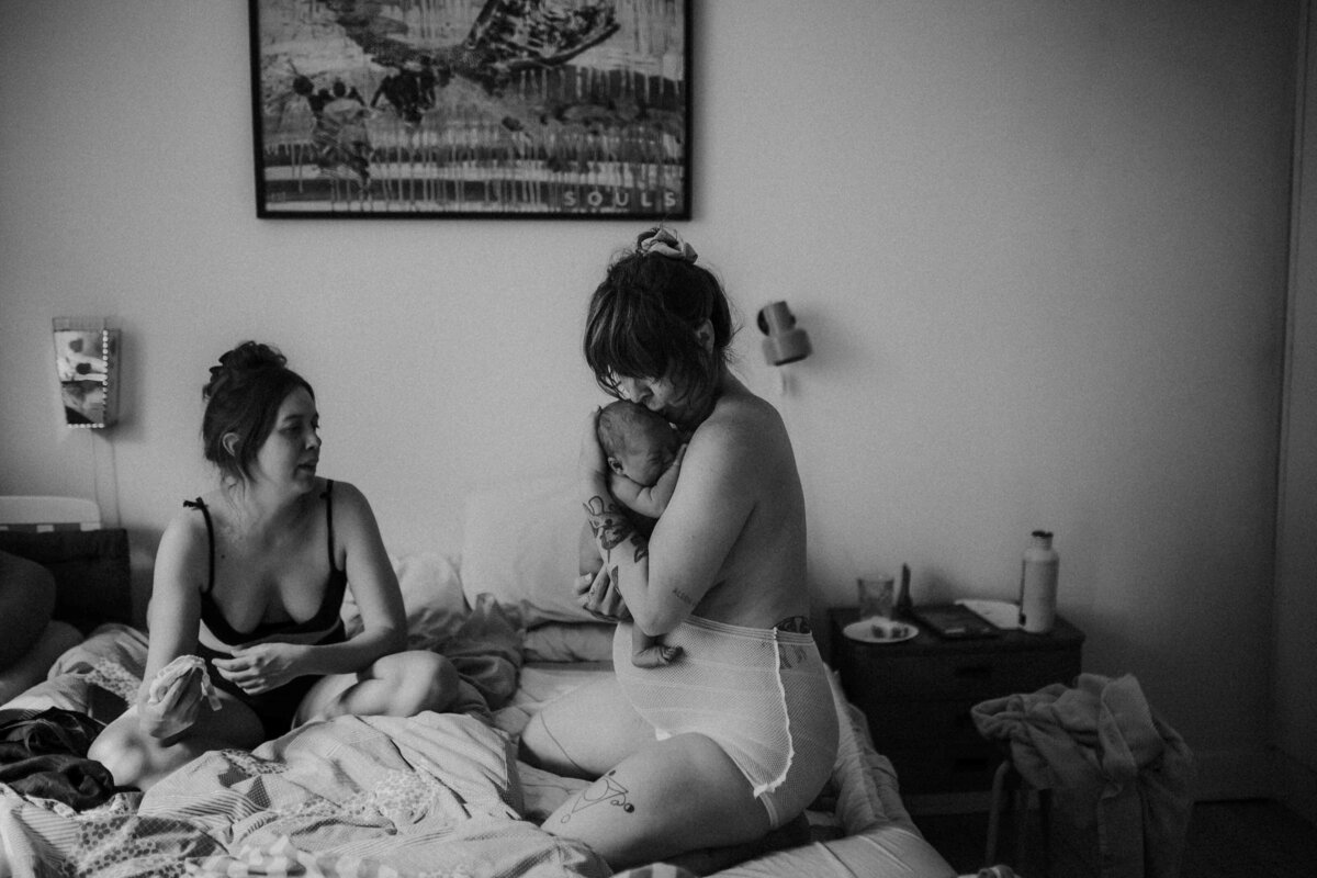 En mamma håller sitt nyfödda barn i famnen. Förlossningsfotografering Göteborg.