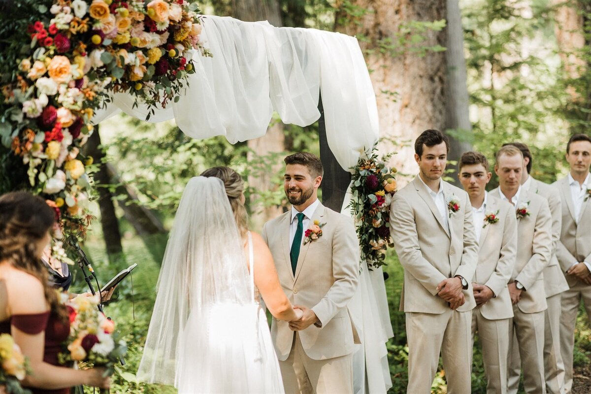 Floral installation and wedding party frame the bride and groom during their wedding ceremony.