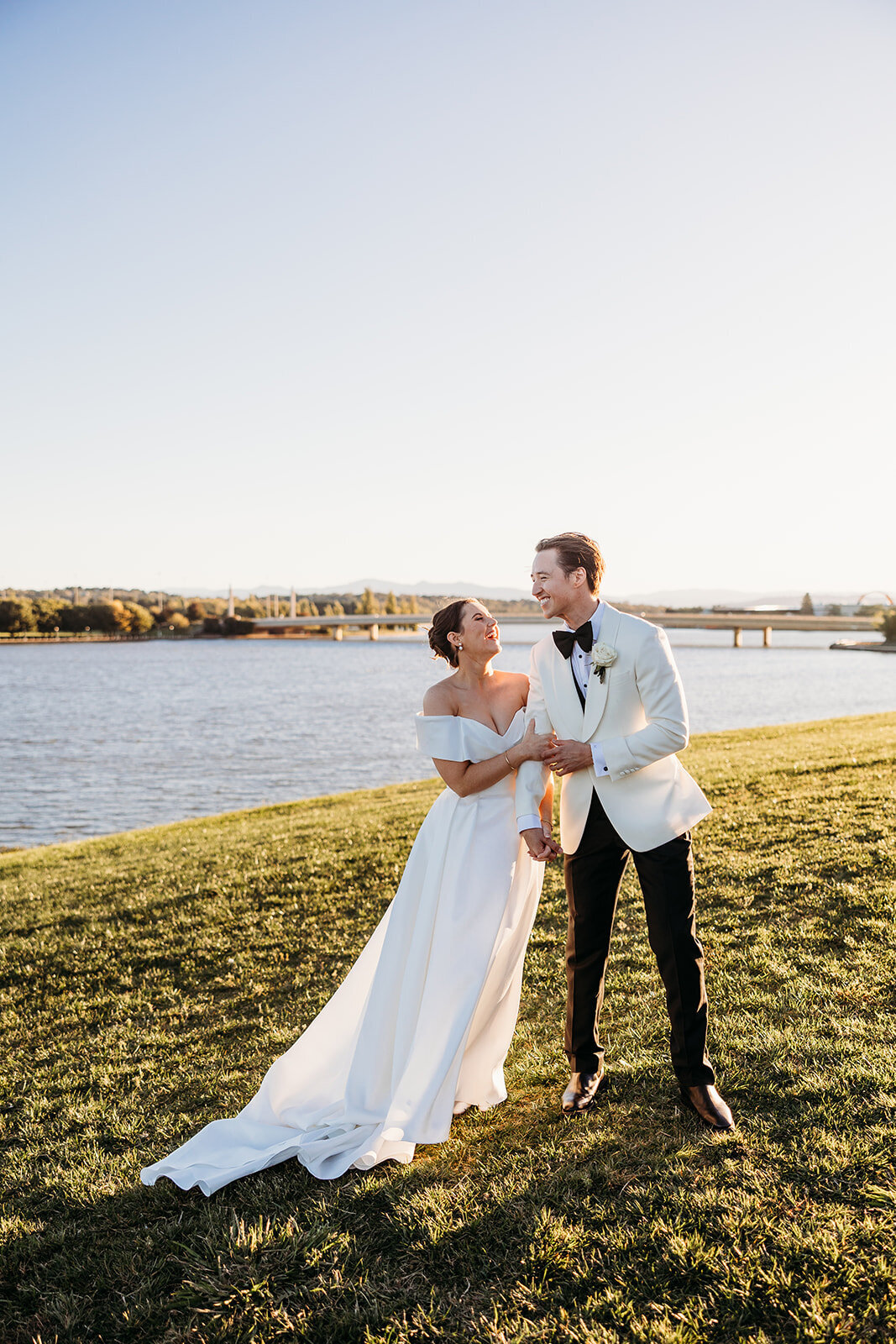 Bride and groom holding each other and laughing during sunset photos