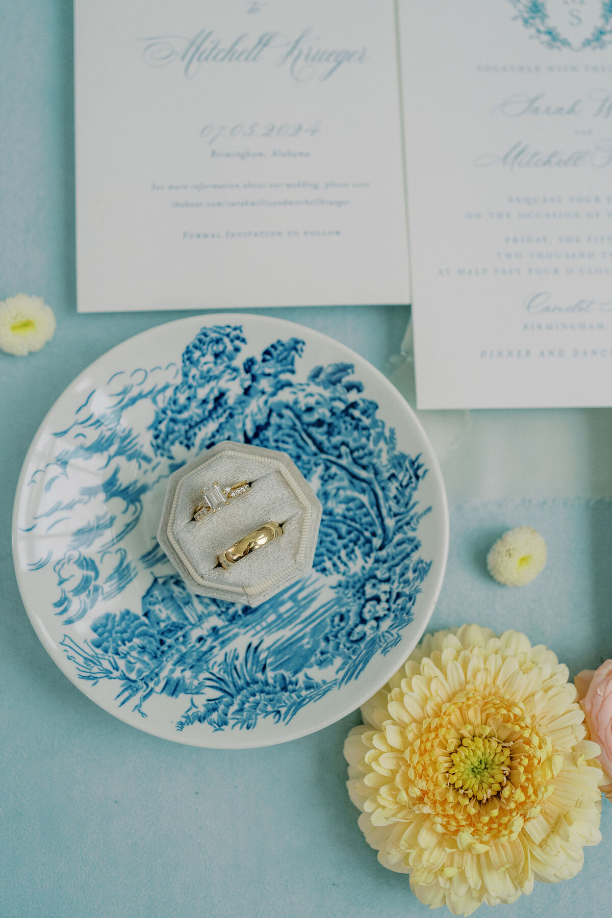 wedding rings sitting on a blue and white dish