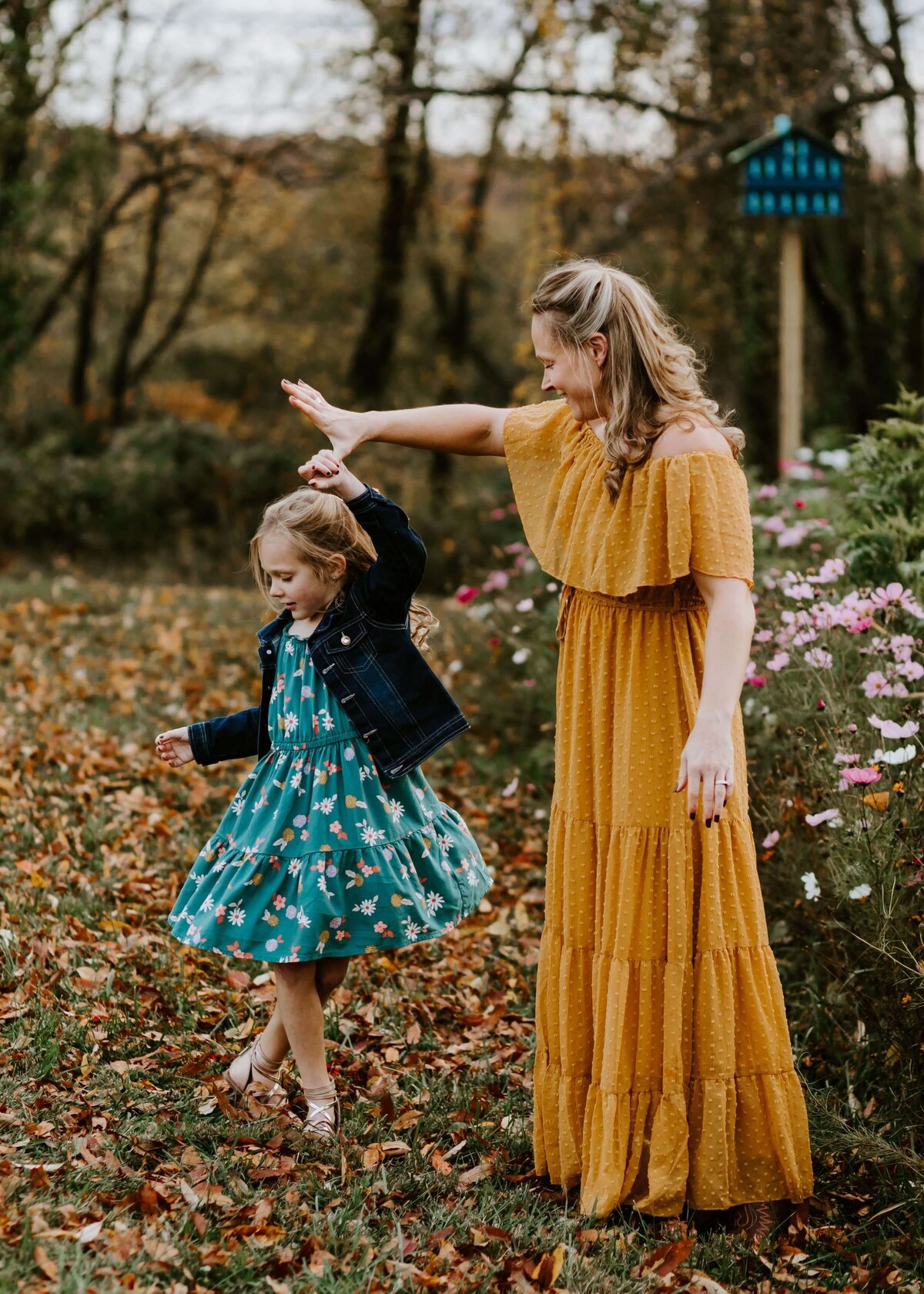A mother and daughter, gracefully twirling in a field, captured by a Pittsburgh family photographer.
