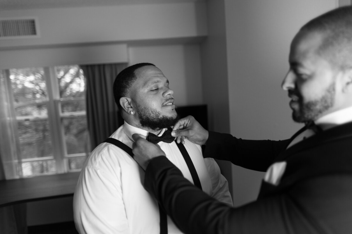 Groomsmen adjusting groom's bowtie