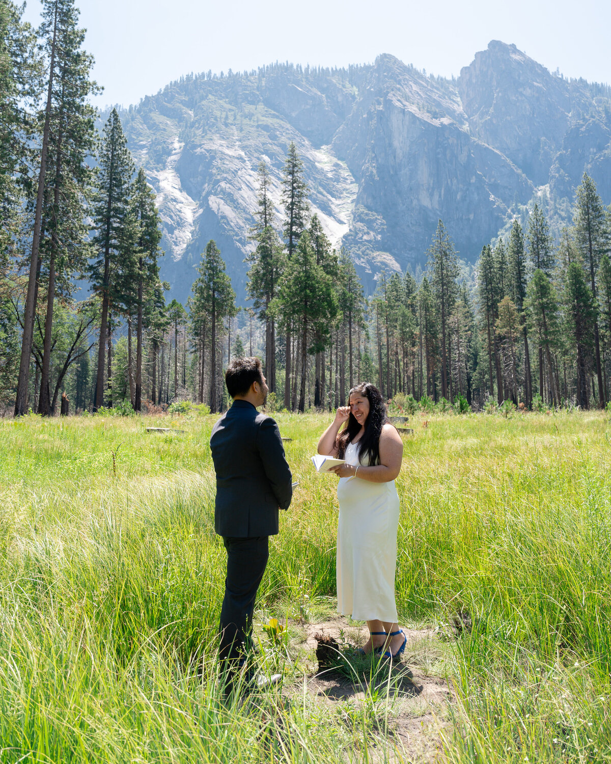 Bride and groom eloping at Yosemite Valley reading intimate wedding vows and crying.