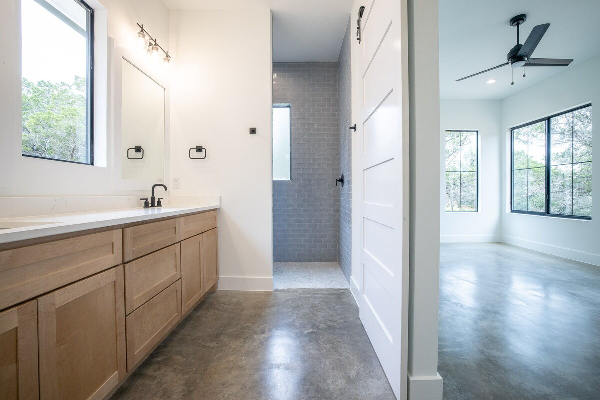 main bathroom with wood vanity, concrete floors and blue shower