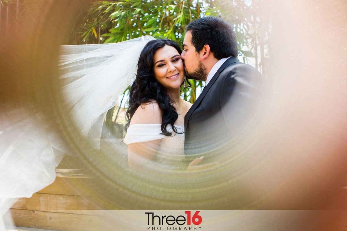 Unique camera affect while Groom kisses the Bride on her cheek