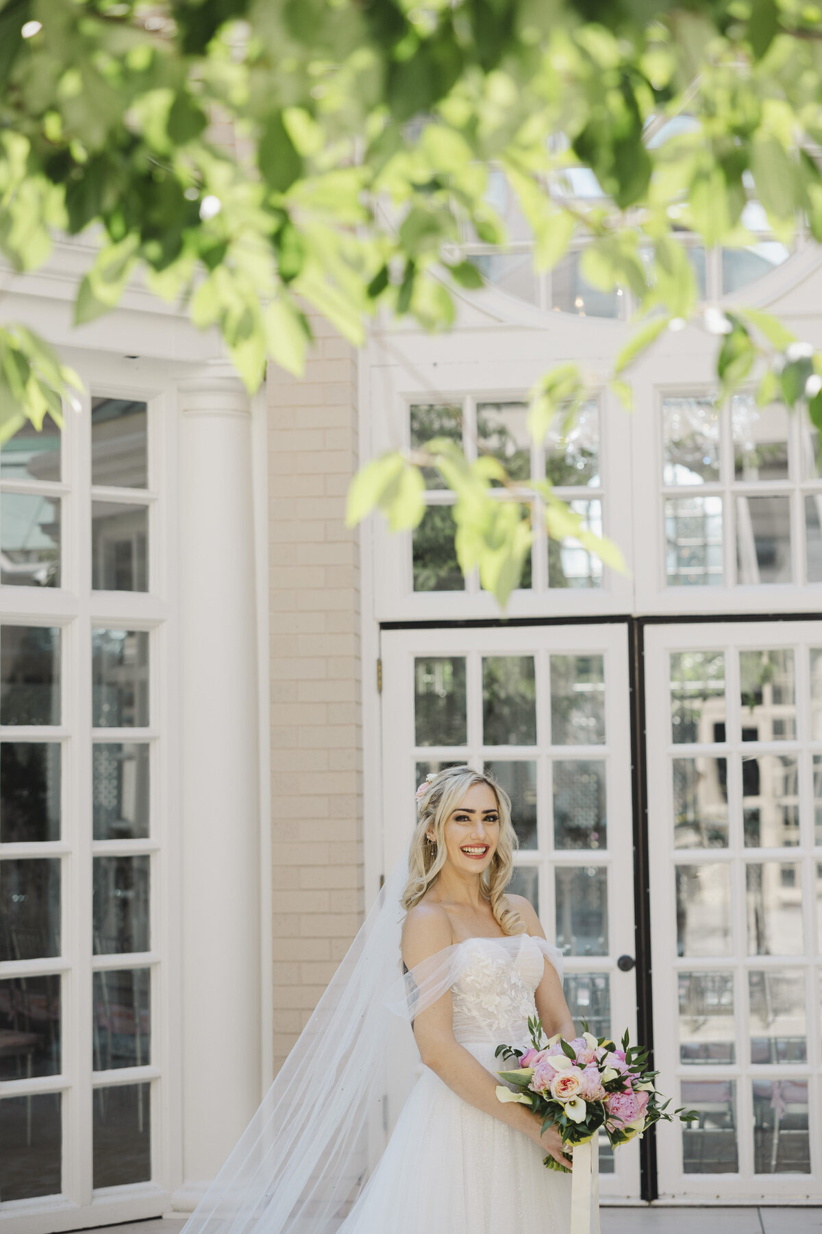 A person in a wedding dress standing outside smiling 