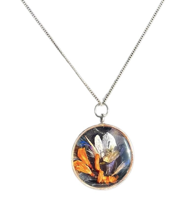 resin neckless with bright orange and blue funeral flowers preserved as a family heirloom