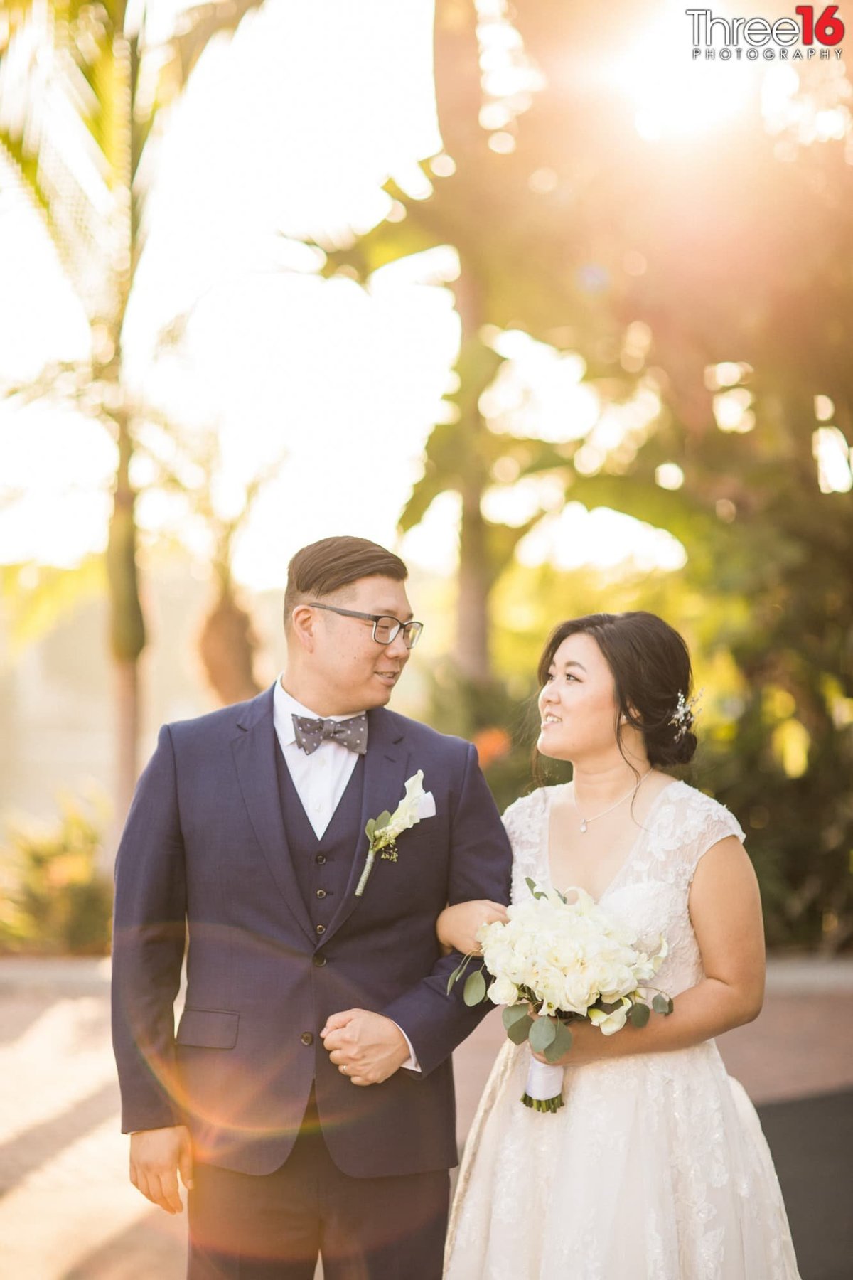 Bride and Groom look at each other as they walk while the sun starts to set