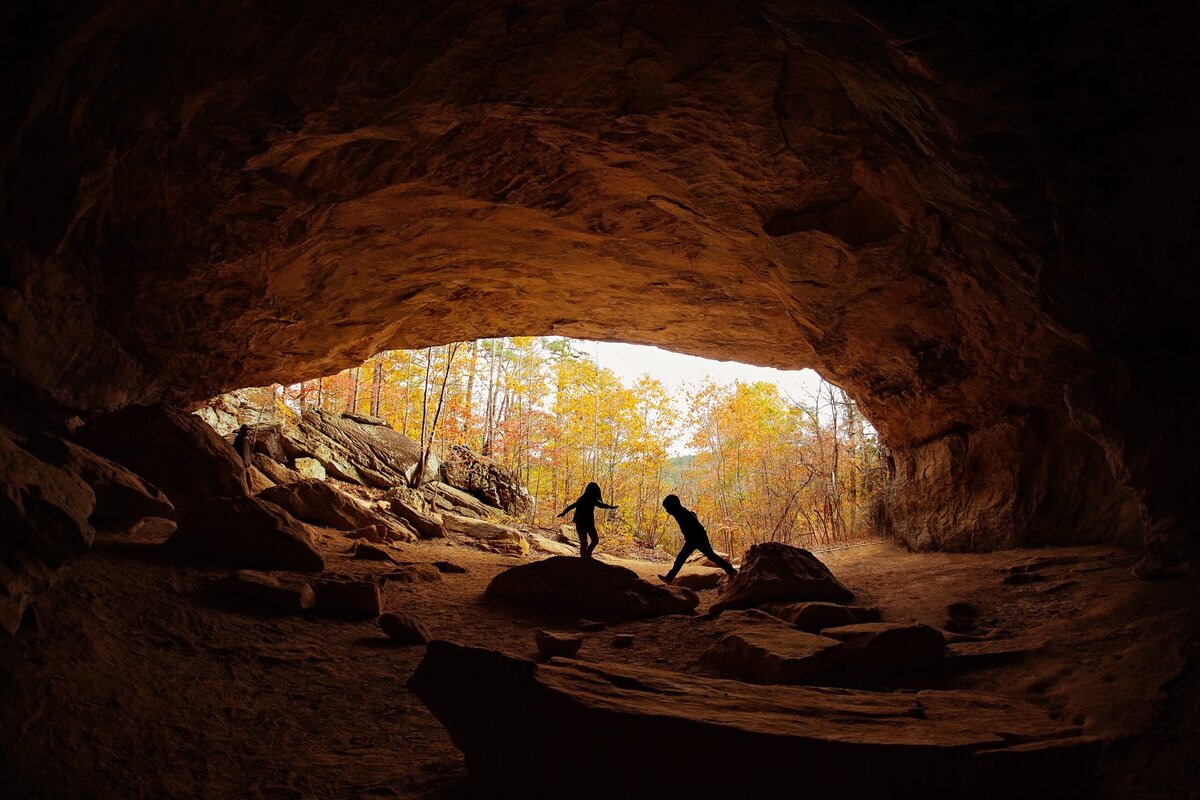 silhoutte image of children playing in a cave